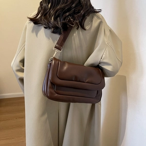 Detail of soft dark brown PU leather crossbody bag with layered flap design and wide strap