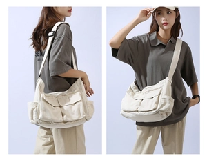 Detail view of large white canvas crossbody bag featuring functional front pockets