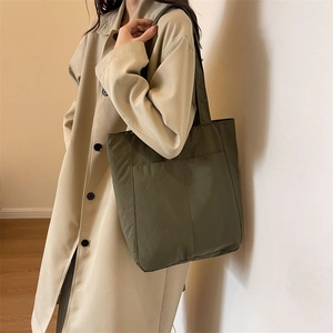 Detail of olive green nylon tote bag featuring external pockets and a durable shoulder strap