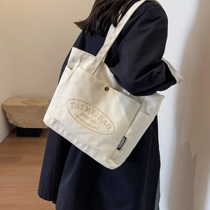 Close-up of minimalist plaid canvas tote bag with front pocket and metal buckle detail