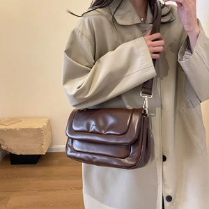 Close-up of the dark brown cloud bag featuring a soft leather texture and golden buckles