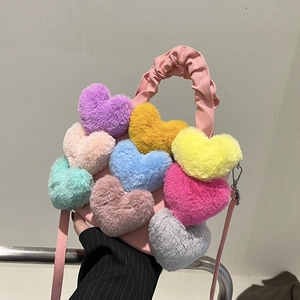 Détail d'un sac bandoulière rose avec des cœurs en peluche colorés et une poignée froncée