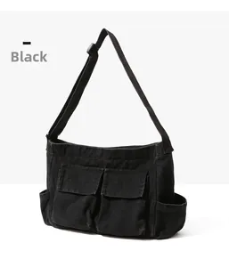 Detail of black canvas crossbody bag showing functional front flap pockets and adjustable strap