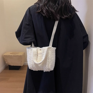Sac à bandoulière blanc en sherpa avec écusson, porté par un mannequin dans un décor épuré