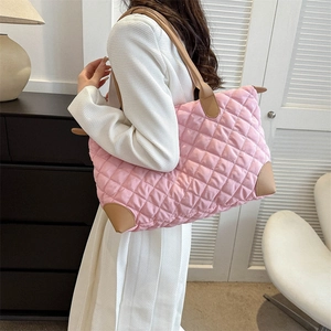 Sac à bandoulière matelassé rose avec anses en cuir présenté par un mannequin chic