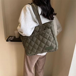 Detail der olivgrünen gesteppten Nylon-Einkaufstasche mit Rautenmuster am Modell