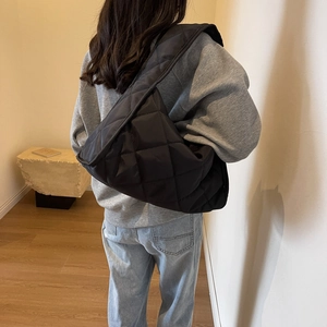 Minimalist black quilted puffer shoulder bag for women worn by a model in casual style