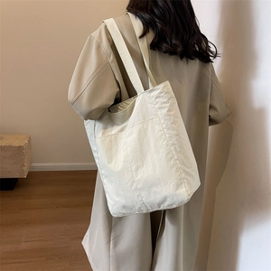 Detail of minimalist cream beige tote bag with a large front pocket and durable nylon fabric