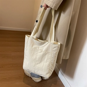 Detail of minimalist beige nylon tote bag with front split pockets for women