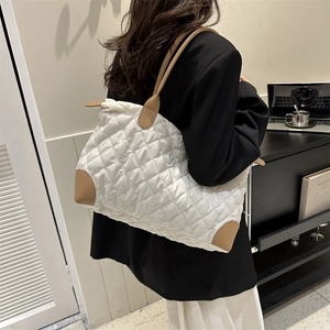 Sac fourre-tout blanc matelassé avec détails en cuir marron porté à l'épaule au bureau