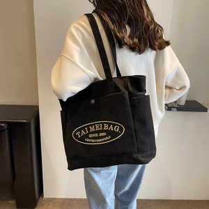 Minimalist black plaid canvas tote bag with gold embroidery shown on model for daily commute