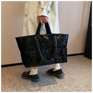 Détail du grand sac cabas noir matelassé avec finition brillante et écusson logo mode
