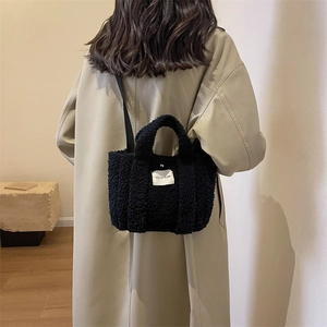Détail macro du sac cabas en peluche noire montrant la texture douce et l'étiquette en tissu