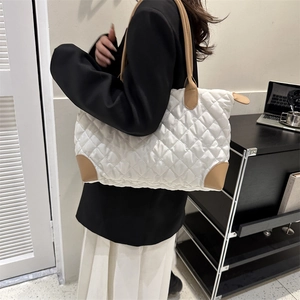 Sac fourre-tout en tissu matelassé avec poignées en cuir camel porté par un mannequin