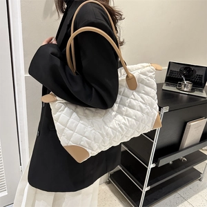 Détail du sac bandoulière matelassé crème avec finitions en cuir marron et fermeture éclair