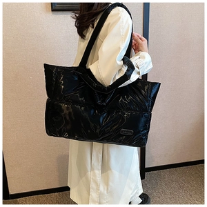 Détail du sac cabas matelassé noir brillant avec étiquette de mode et larges bandoulières