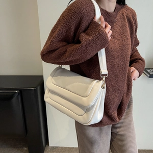 On-shoulder view of the beige padded crossbody bag with horizontal quilted faux leather