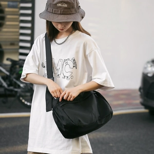 Detail of black nylon messenger bag with adjustable strap in casual outdoor streetwear style