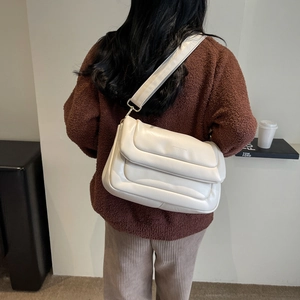 Back view of a model wearing a minimalist off-white puffy PU leather crossbody bag