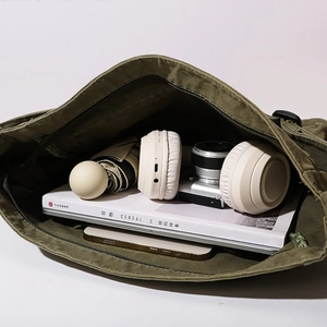 Olive green canvas crossbody bag showing large capacity with laptop and daily essentials