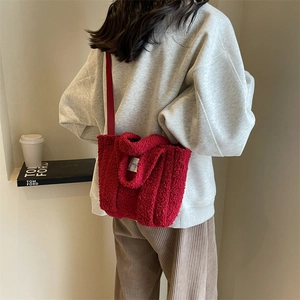 Détail d'un sac cabas en peluche rouge doux avec plaque métallique et bandoulière