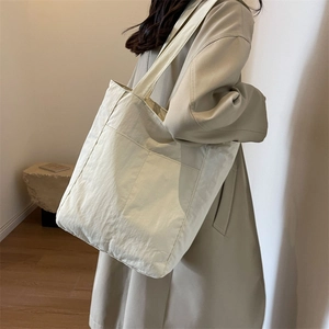 Minimalist beige canvas tote bag with large outer pocket and shoulder strap for women