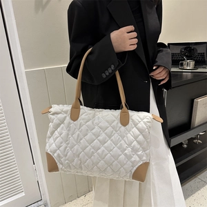 Grand sac cabas matelassé blanc avec anses camel porté par un mannequin dans un bureau