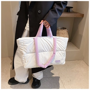 Détail du sac cabas matelassé avec des anses lavande et une étiquette mode