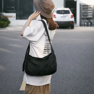 Close-up of the large black nylon messenger bag with wide shoulder strap and zippers