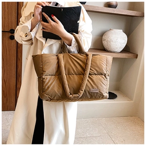 Détail d'un sac cabas matelassé marron avec étiquette mode et bandoulières rembourrées souples
