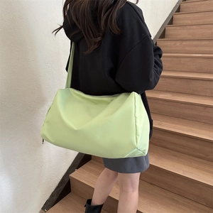 Back view of a large mint green nylon crossbody bag styled with a black hoodie