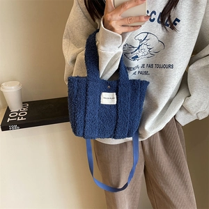 Détail du sac cabas en polaire bleu marine montrant la texture pelucheuse et l'étiquette