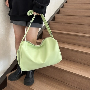 Detail view of large light green nylon crossbody bag showing the side zipper pocket