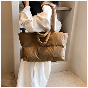 Dettaglio della borsa shopper imbottita marrone caffè con etichetta moda in un set moderno