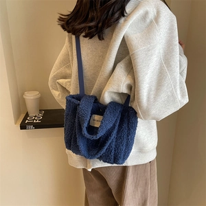 Détail du sac à bandoulière en peluche bleue avec étiquette tissée sur polaire teddy