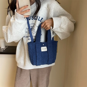 Sac fourre-tout bleu en peluche avec bandoulière et écusson de marque sur mannequin