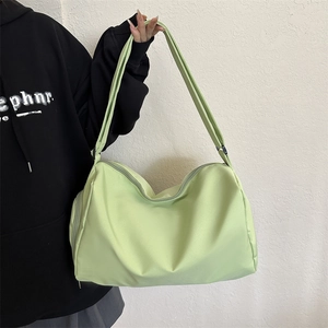 Close-up of mint green nylon tote bag featuring durable zippers and adjustable strap