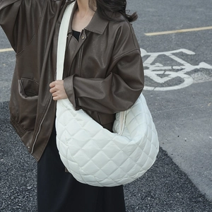 Photo de rue d'un sac demi-lune blanc en nylon matelassé porté par un mannequin