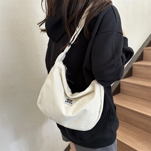 Detail of off-white corduroy shoulder bag featuring a cute brown bear embroidery