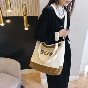 Detail view of canvas tote bag with SUN smile print and dual strap design on model