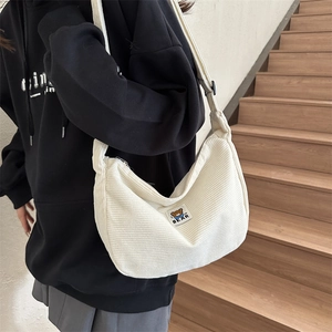 Detail of off-white corduroy crossbody bag featuring a cute bear patch and striped texture