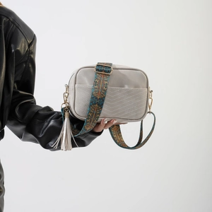 Detail of grey PU leather crossbody bag with V-quilted pattern and ethnic strap