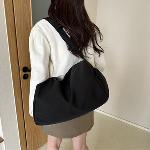 Minimalist black large capacity crossbody tote bag worn by model in minimalist indoor setting