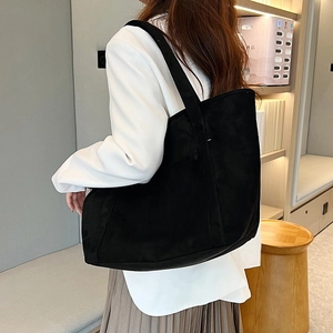Model wearing a large matte black tote bag with long handles for daily commuting