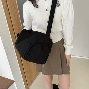 Minimalist black oxford cloth crossbody bag with front zipper pocket and adjustable strap