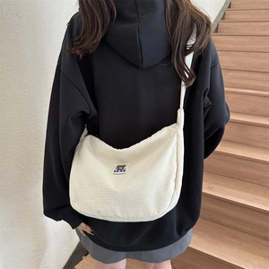 Detail view of cream corduroy crossbody bag with a cute bear patch on a black hoodie