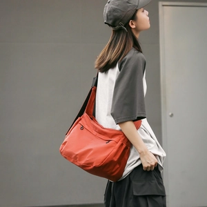 Bright orange waterproof nylon crossbody bag with wide adjustable shoulder strap detail
