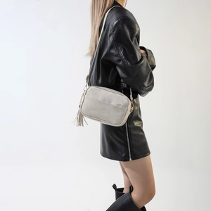 Detail of minimalist beige PU leather crossbody bag with fringe tassel and gold hardware