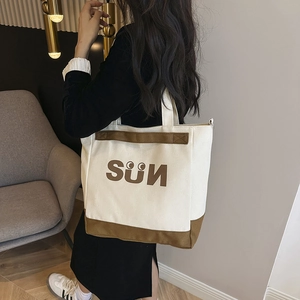 Detailed back view of a model carrying the large canvas tote bag with SÜN letter print