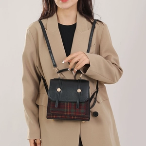 Détail d'un sac à main à carreaux avec boucles dorées porté sur un blazer beige